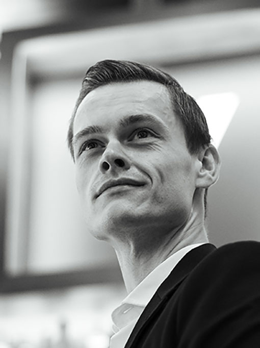 A close-up of a man, taken slightly from below: he is wearing a suit and looking upwards, outwards.