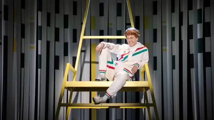 En man med hånfullt leende sitter avslappnad uppe i en hög stol.