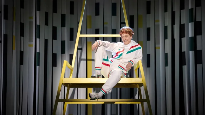 En man med hånfullt leende sitter avslappnad uppe i en hög stol.