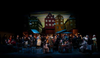 En grupp människor på en scen - i bakgrunden husfasader.