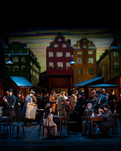 A group of people on a stage - in the background house facades.