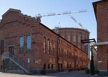 En stor tegelbyggnad med trappgavel, i bakgrunden syns en cylindrisk tegelbyggnad.