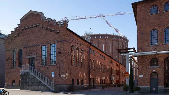 En stor tegelbyggnad med trappgavel, i bakgrunden syns en cylindrisk tegelbyggnad.