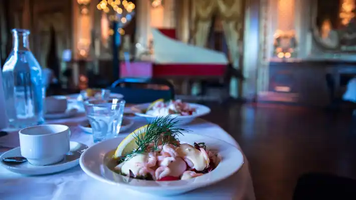 Ett bord dukat med en räksallad, vattenglas och en kaffekopp.