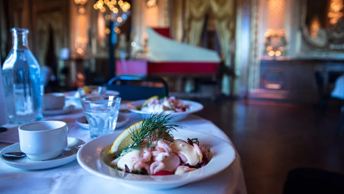 Ett bord dukat med en räksallad, vattenglas och en kaffekopp.