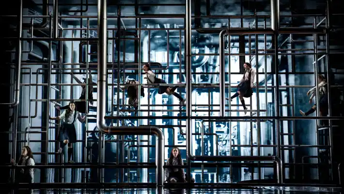 En scen fylld med rör i vilka flera kvinnor klättrar.