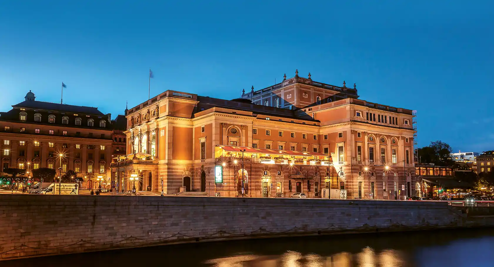 A large building by a stream against a clear evening sky.