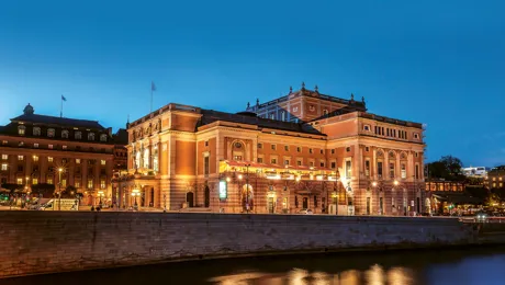 En stor byggnad vid ett vattendrag mot en klar kvällshimmel.