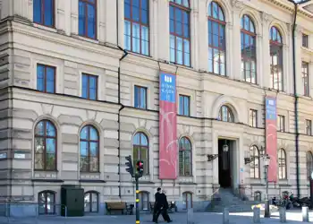 En stor byggnad med många stora fönster och en trappa som leder mot ingången.