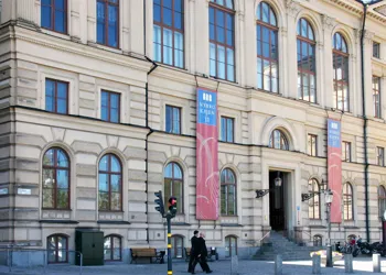 En stor byggnad med många stora fönster och en trappa som leder mot ingången.