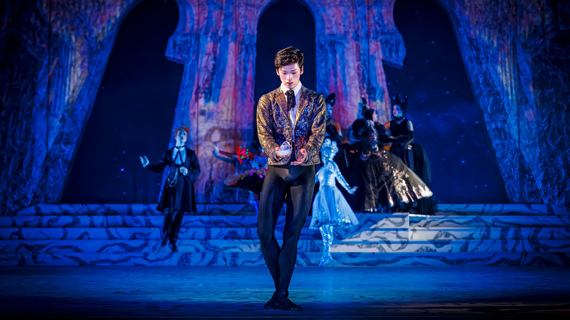 En kostymklädd man håller en sko i sin hand.