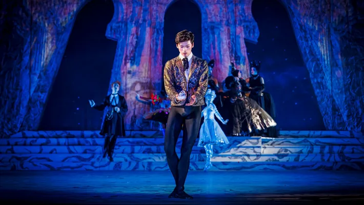 A man in a suit holds a shoe in his hand.