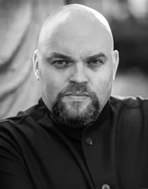 Närbild på en man med allvarlig min, klädd i mörk kostymjacka.