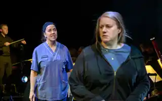 En kvinna i sjukhuskläder står snett bakom en annan kvinna, i vanliga kläder.