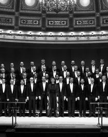 A large group of men in suits and one woman are standing under a dome.