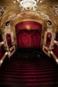 View of a stage from a richly decorated auditorium in red and gold.