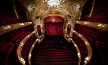 View of a stage from a richly decorated auditorium in red and gold.