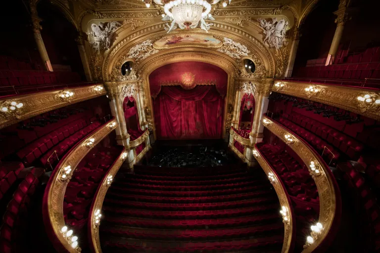 View of a stage from a richly decorated auditorium in red and gold.