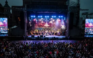 En stor mängd människor framför en upplyst scen, på sidorna två stora videoskärmar.