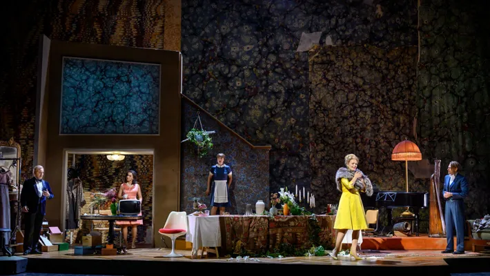 En stor scenbild med flera personer som rör sig i en rörig rumsmiljö.