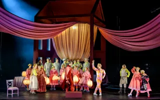 En stor grupp människor med lyktor samlas under en baldakin.