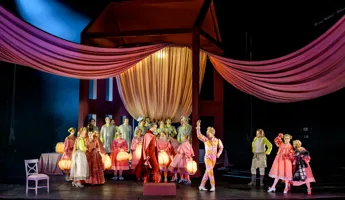 En stor grupp människor med lyktor samlas under en baldakin.