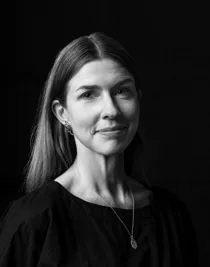 Svart-vit närbild på en kvinna med långt hår och ett långt halsband.