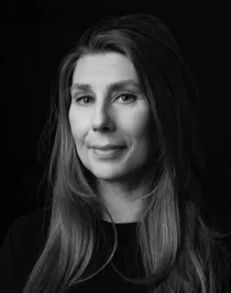 Svart-vit närbild på en leende kvinna med långt mörkt hår.