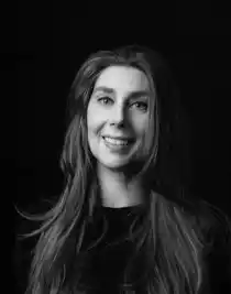 Black and white close-up of a smiling woman with long dark hair.