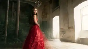 En kvinna i röd klänning står i ett rum med fönster, i vänstra hörnet växer en skog.