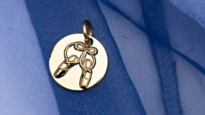 Blå tyll och en berlock i guld med ett par tåskor.