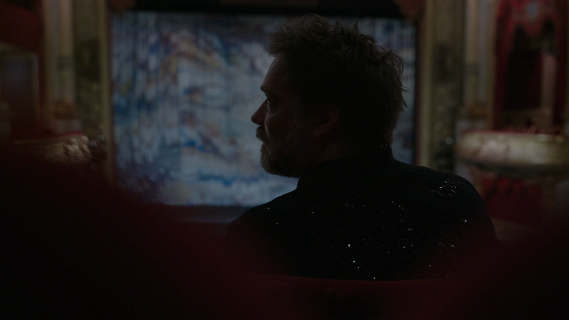 En mansprofil i motljus , i bakgrunden en upplyst scen.