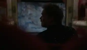 En mansprofil i motljus , i bakgrunden en upplyst scen.