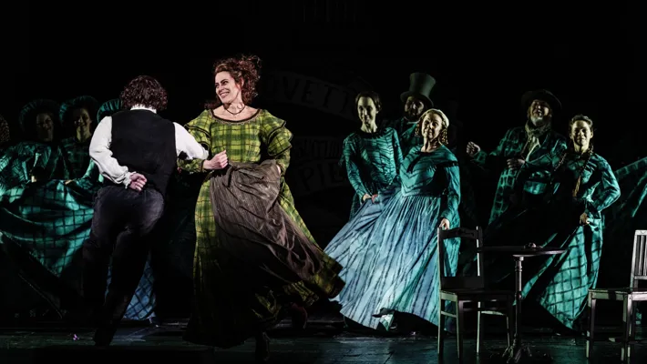 A group of people on a stage, a couple dancing in the foreground.