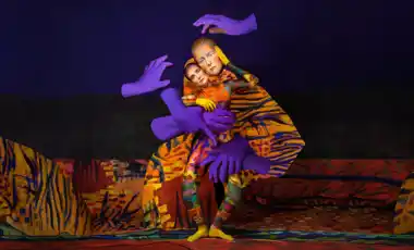 En kvinna i en färgglad kostym och med stora lila händer svävandes runt henne.