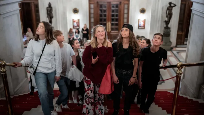 A group of people walking up a red carpeted staircase.