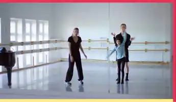 En kvinna en ung tjej och en man provar rörelser tillsammans i en repetitionslokal.