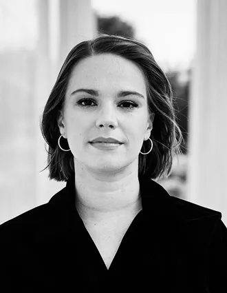 En närbild på en kvinna i mörka kläder, kort pagefrisyr.