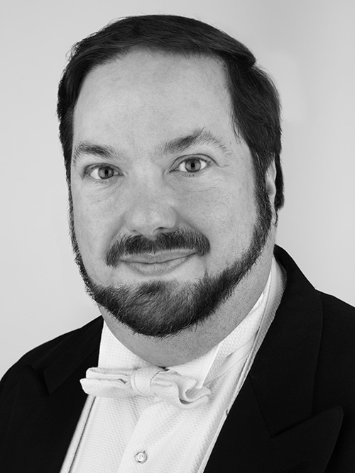 A close-up of a man with a beard wearing a tailcoat.