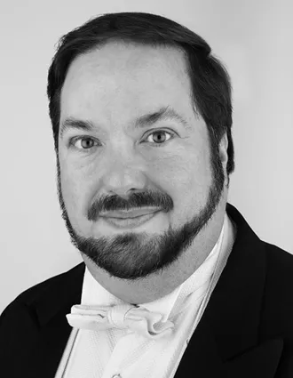 Nn närbild på en man med skägg klädd i frack.