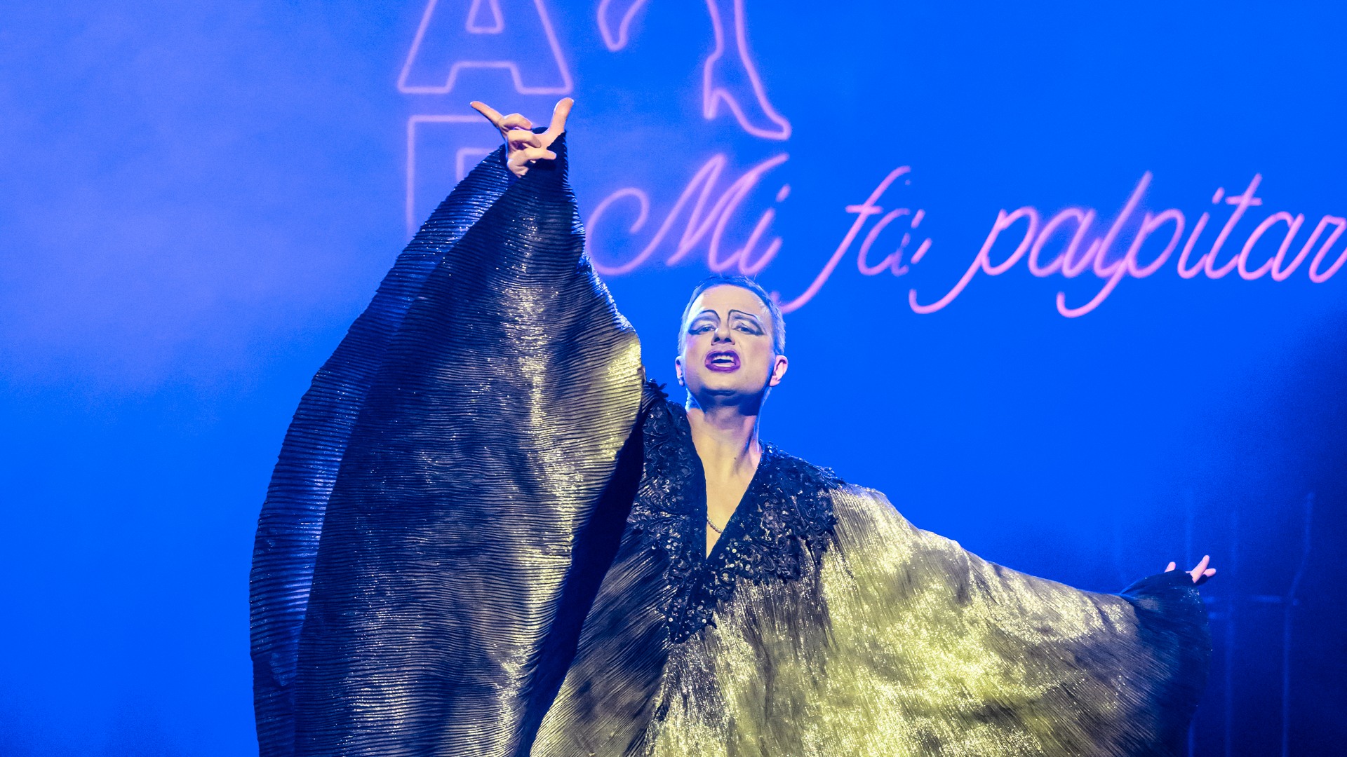 En man står på en scen och håller i ett stort tygstycke.