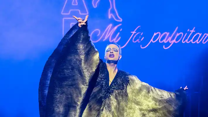 En man står på en scen och håller i ett stort tygstycke.