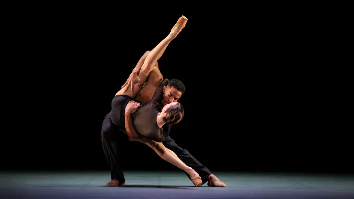 A man and a woman doing an advanced dance move on a stage.
