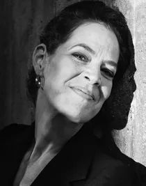 Svartvit bild på kvinna med lätt lutat huvud mot en vägg.