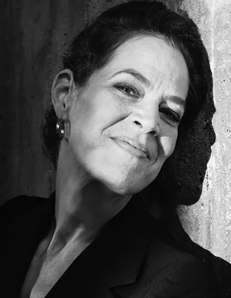 Svartvit bild på kvinna med lätt lutat huvud mot en vägg.