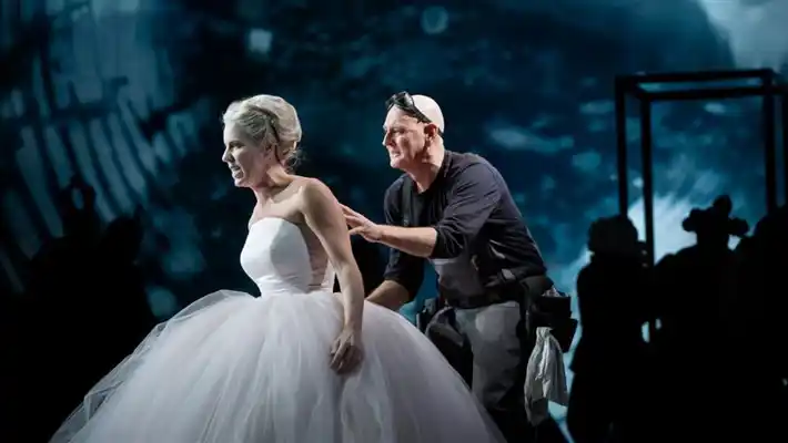 En kvinna i en vit tyllklänning hålls i av en man.