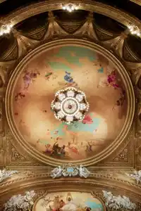 View of a roof and several balconies, a large ceiling painting and a magnificent chandelier in the center.