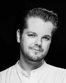 Närbild på en ung man med ljus, kraglös skjorta.