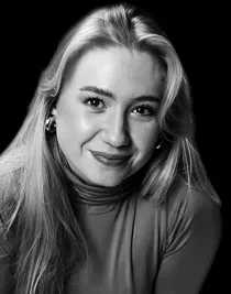 En kvinna med långt blont hår mot en mörk bakgrund.