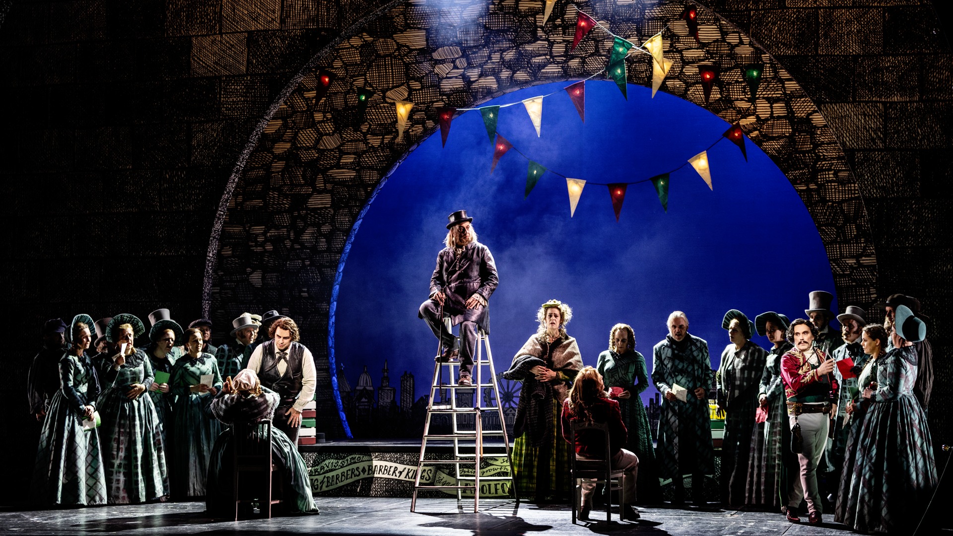 A group of people on a stage, one man sitting on a ladder.